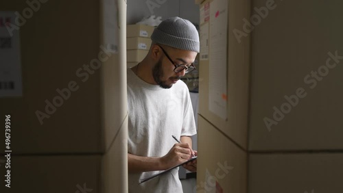 Asian man online seller checking stock and Inventory before sending to the customer. E-commerce business owner working in store warehouse.