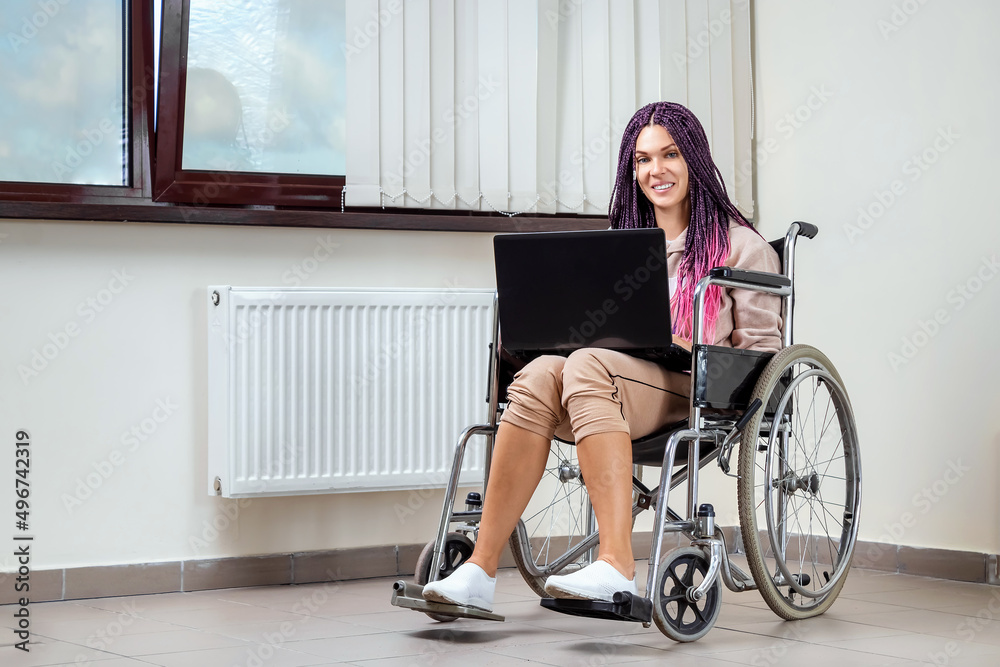 Beautiful modern disabled girl working on a laptop in a wheelchair. Work from home, work for the disabled, freelancing, remote work. Beautiful modern disabled girl working on a laptop in a wheelchair. Work from home, work for the disabled, freelancing, remote work.