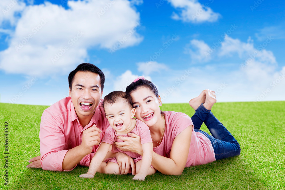Happy parents and their baby lying on the park Happy parents and their baby lying on the park