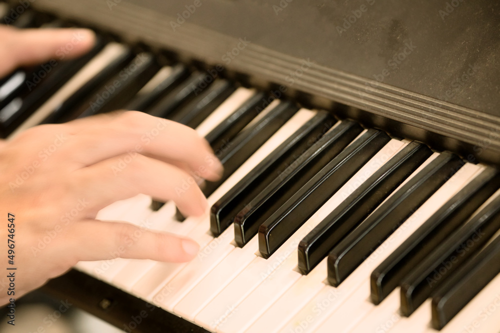 Close-up of musician's hand playing piano in class or music performance.