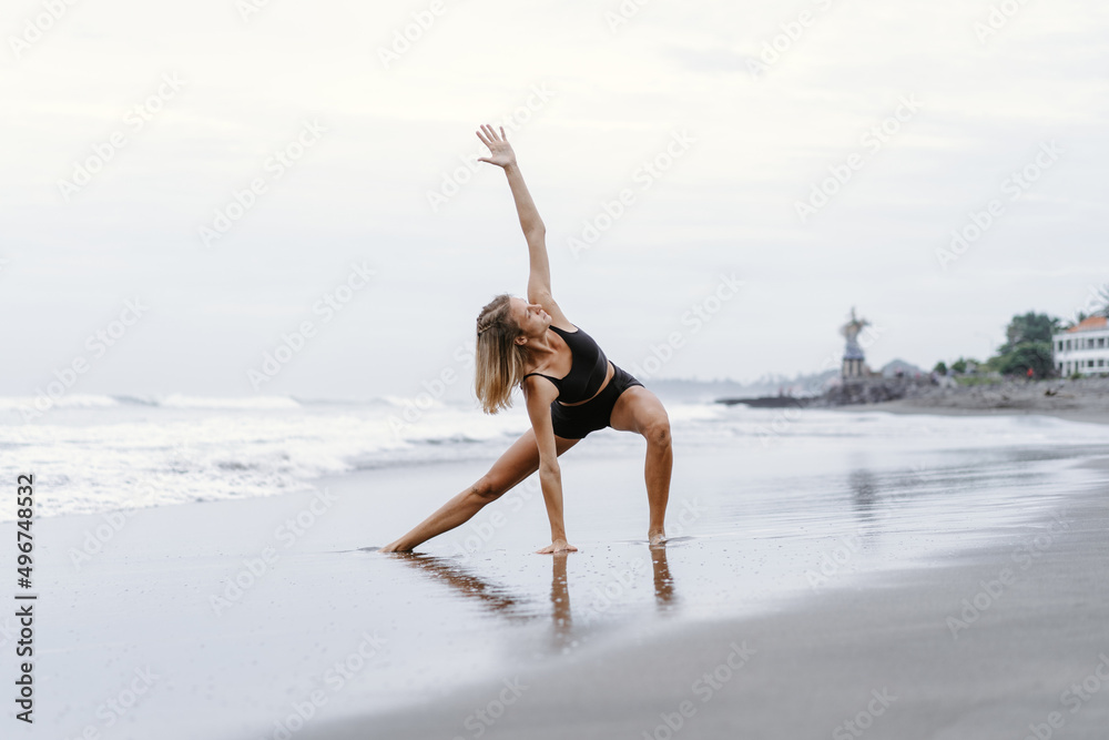 Sporty woman doing mountain climber exercise - run in plank to burn fat. Sunset beach, blue sky background. Healthy lifestyle at tropical island yoga retreat, outdoor activity, family summer vacation.