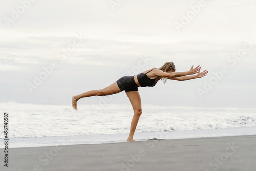 Sporty woman doing mountain climber exercise - run in plank to burn fat. Sunset beach, blue sky background. Healthy lifestyle at tropical island yoga retreat, outdoor activity, family summer vacation. photo