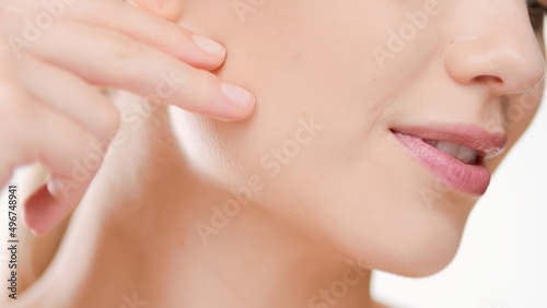 Extreme close-up shot of young white-skinned woman gently touches her face on white background | Beauty care commercial concept