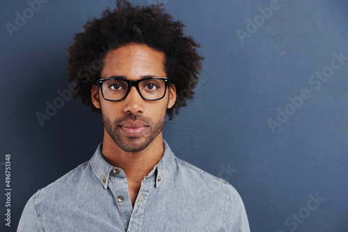 So you think youre smart. Portrait of a handsome young man wearing glasses on a gray background.