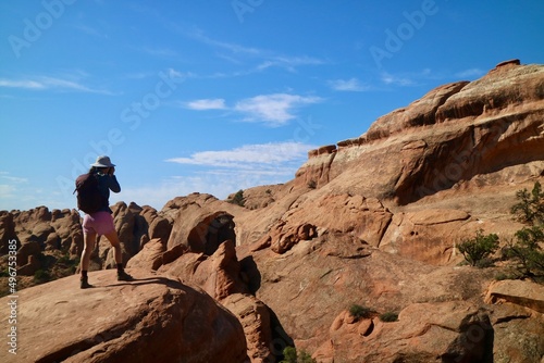 Explorer taking photos on rock. Arches National Park, Utah.