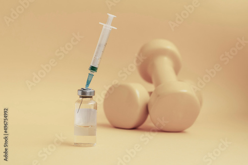 syringe is stuck in a jar, there are dumbbells on a yellow background next to it, a horizontal photo. the concept of doping in sports, steroids, testosterone and other drugs prohibited in sports.