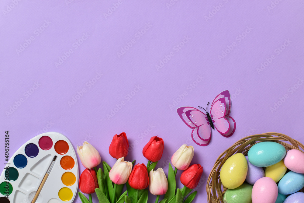 Easter background with painted eggs, paints and tulips. Copy space. Flat lay, top view