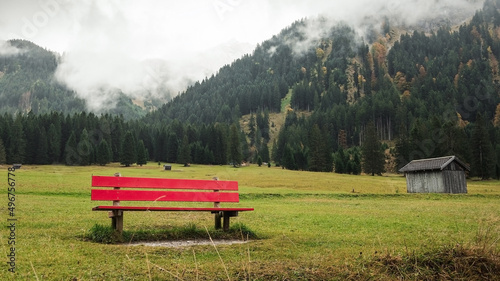 red bench in alpine countryside. Foggy mountains in Tyrol. 