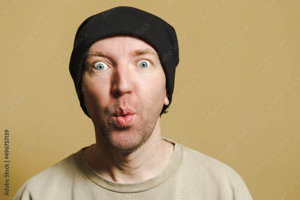 A man in a black cap looks with surprise. Portrait of a young man making faces A man in a black cap looks with surprise. Portrait of a young man making faces
