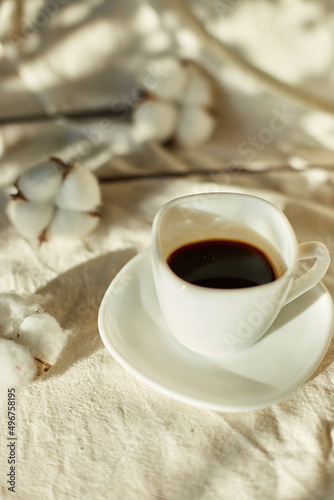 Cup of coffee in bed with cotton flowers,  morning mood, Organic and natural linen cotton textile bedclothes, copy space.