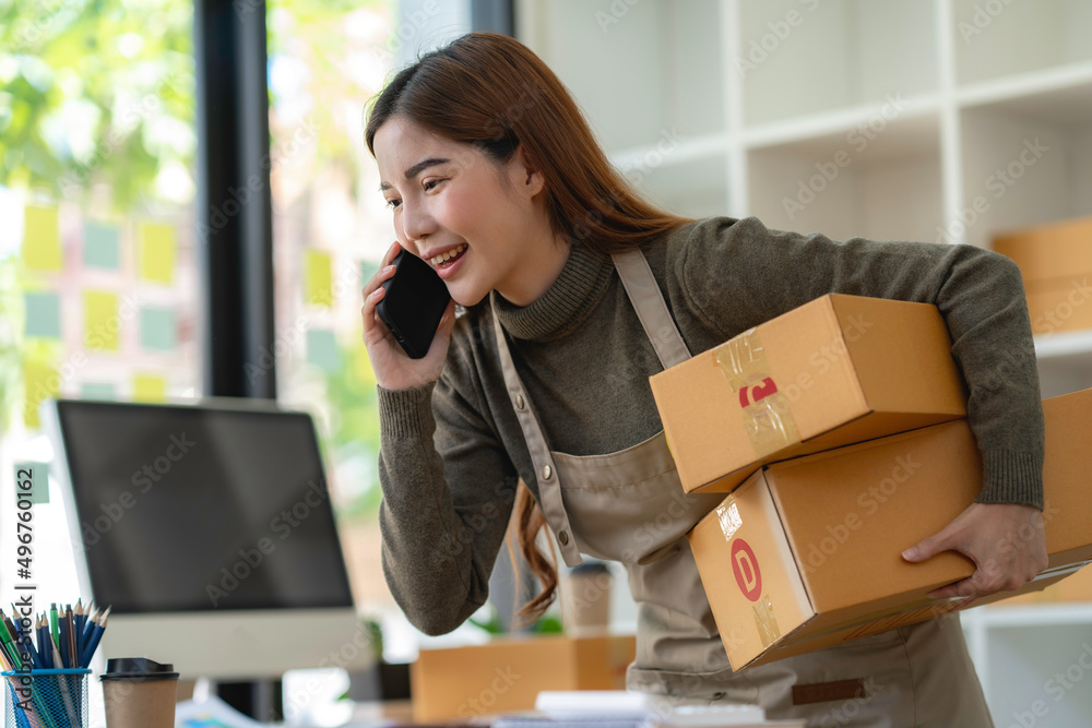 Asian Small business entrepreneur SME working with box and On the phone to confirm orders with customers at home, SME e-commerce digital technology concept. Asian Small business entrepreneur SME working with box and On the phone to confirm orders with customers at home, SME e-commerce digital technology concept.