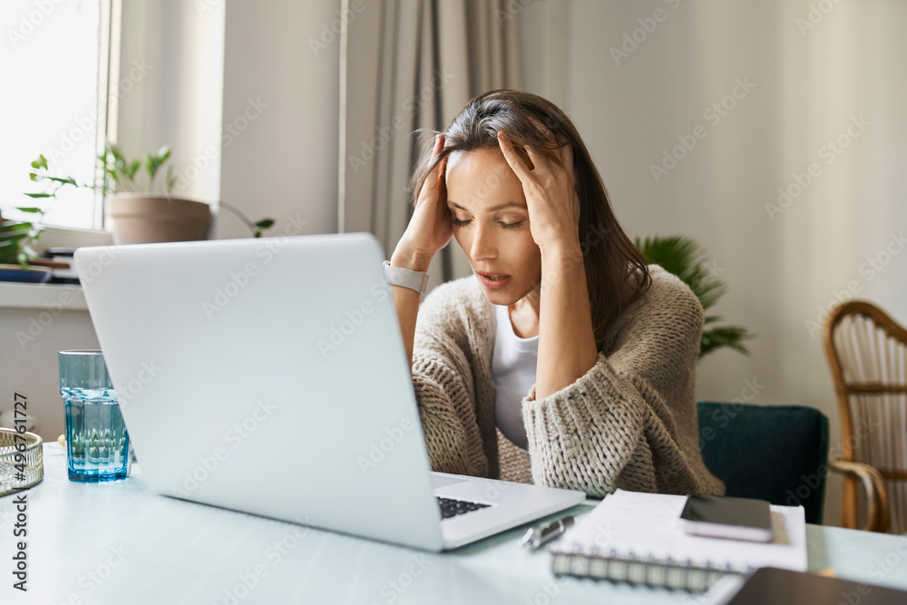 Stressed freelancer sitting with laptop at desk Stressed freelancer sitting with laptop at desk