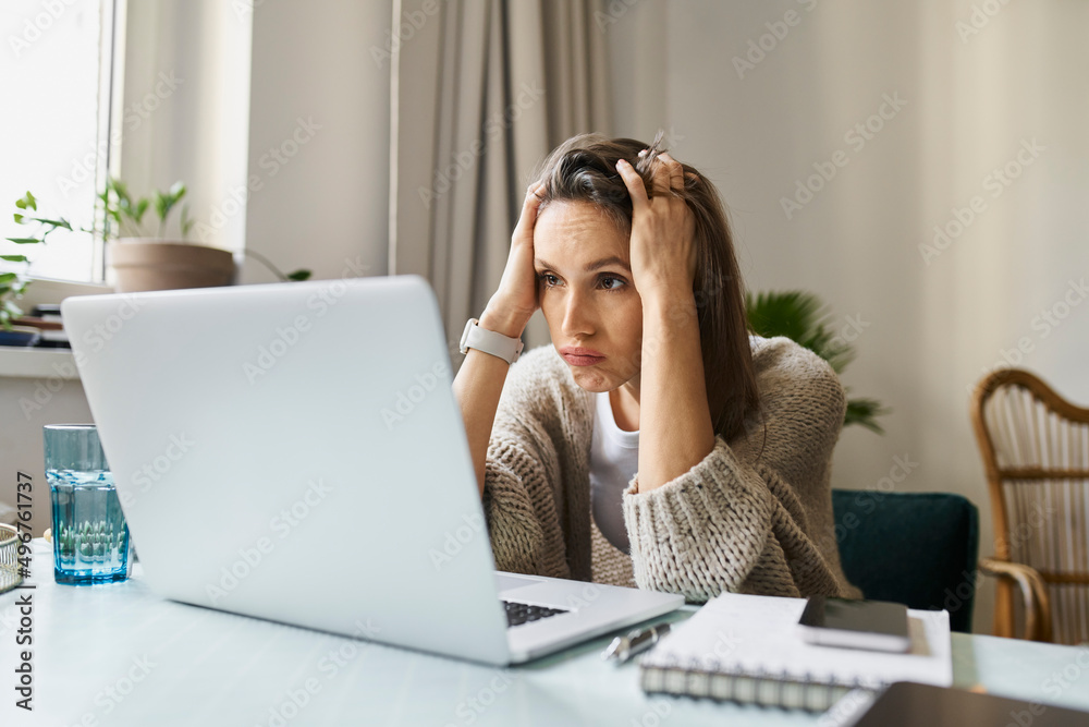 Stressed freelancer looking at laptop working from home Stressed freelancer looking at laptop working from home