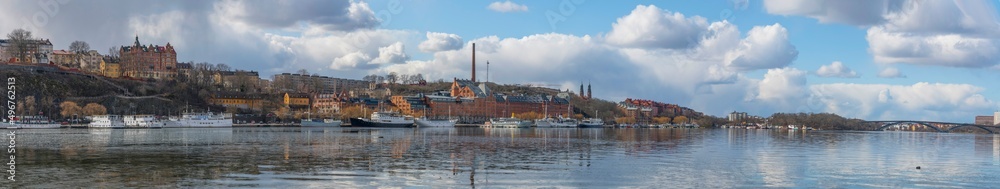 Panorama view with boats, apartment houses and an old brick brewery buildings at the waterfront Norr Mälarstrand a sunny spring day in Stockholm
