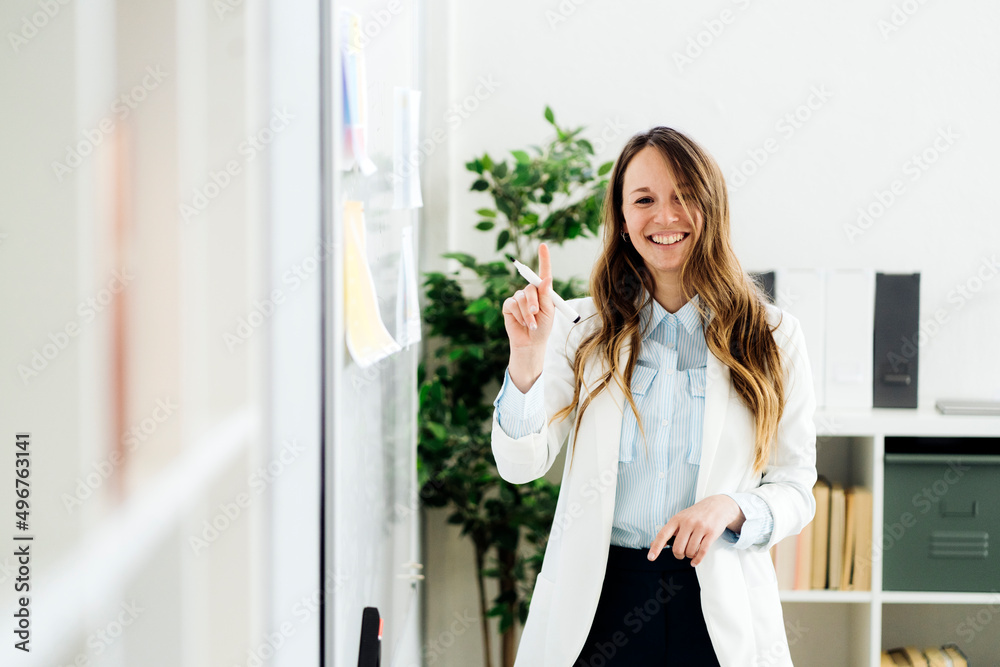 Smiling businesswoman holding felt tip pen in office Smiling businesswoman holding felt tip pen in office