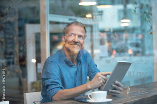 Wallpaper Mural Smiling businessman with tablet PC sitting at table by window in cafe Torontodigital.ca