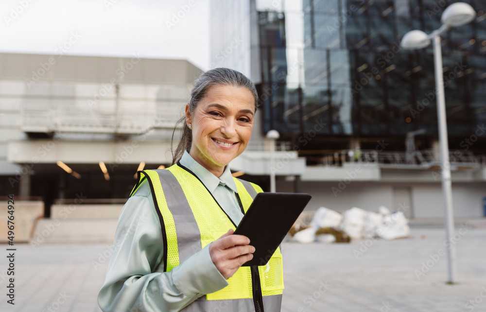 Happy engineer with tablet PC standing outside modern building
