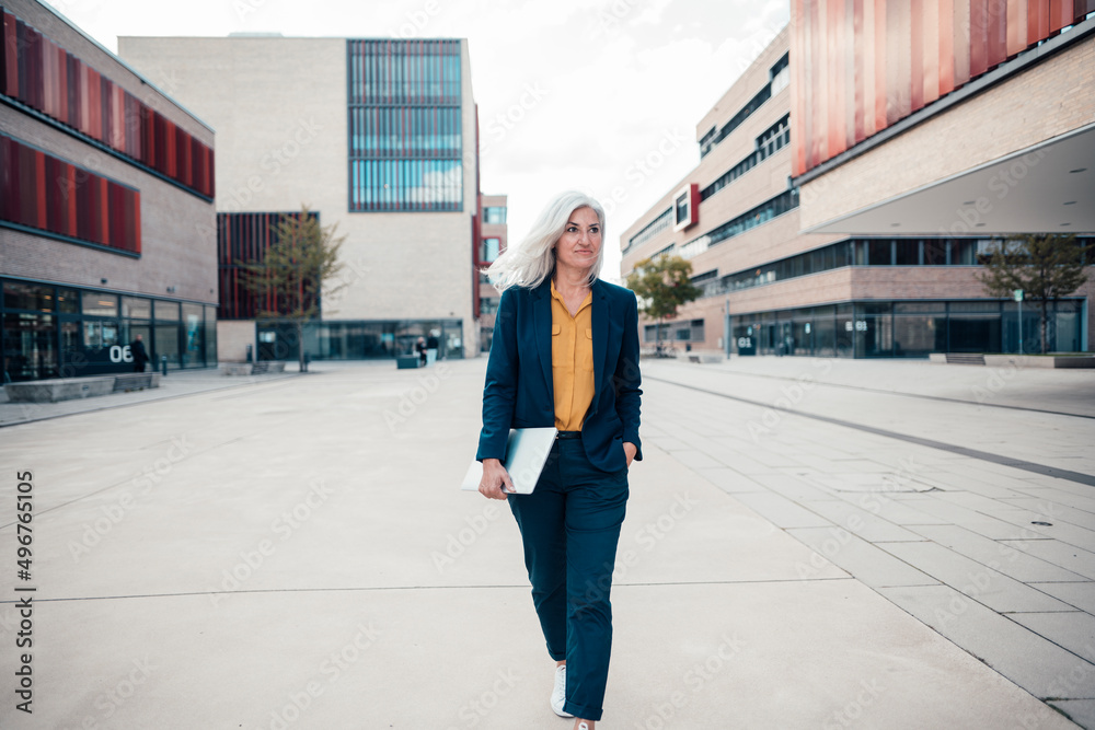 Businesswoman with laptop walking at office park Businesswoman with laptop walking at office park