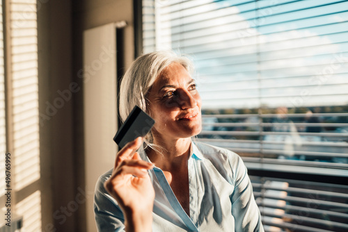 Thoughtful businesswoman holding credit card in office photo