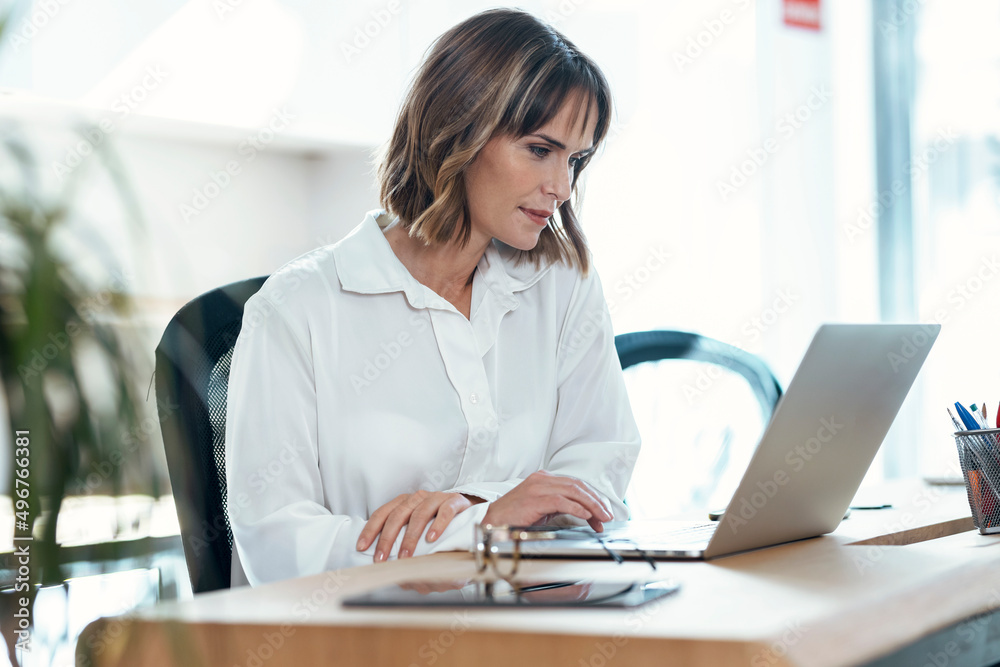 Businesswoman using laptop at desk in office Businesswoman using laptop at desk in office