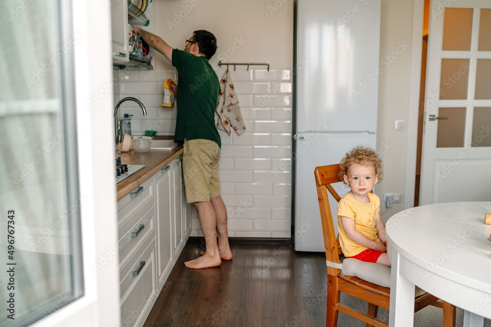 Girl sitting on chair with father in kitchen Girl sitting on chair with father in kitchen