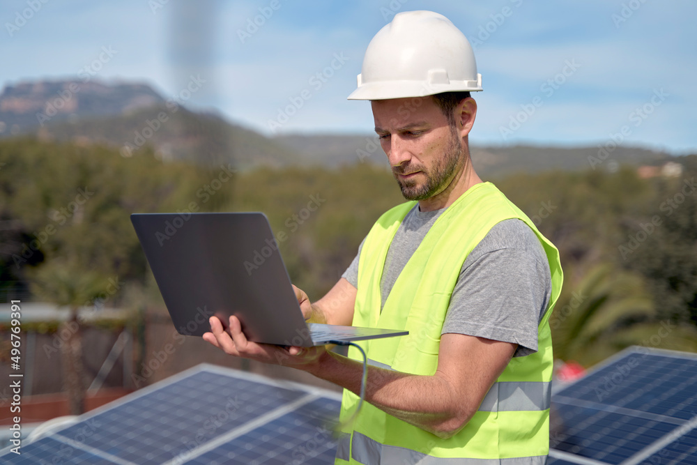 Engineer wearing hardhat using laptop on sunny day Engineer wearing hardhat using laptop on sunny day