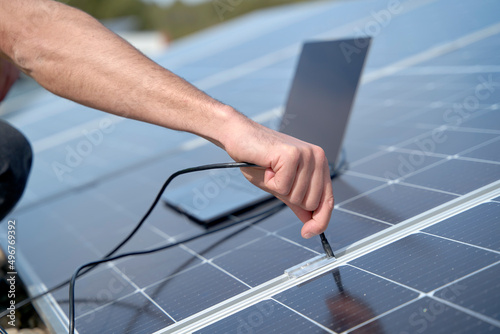 Engineer plugging in power supply cable charger of laptop to solar panels photo