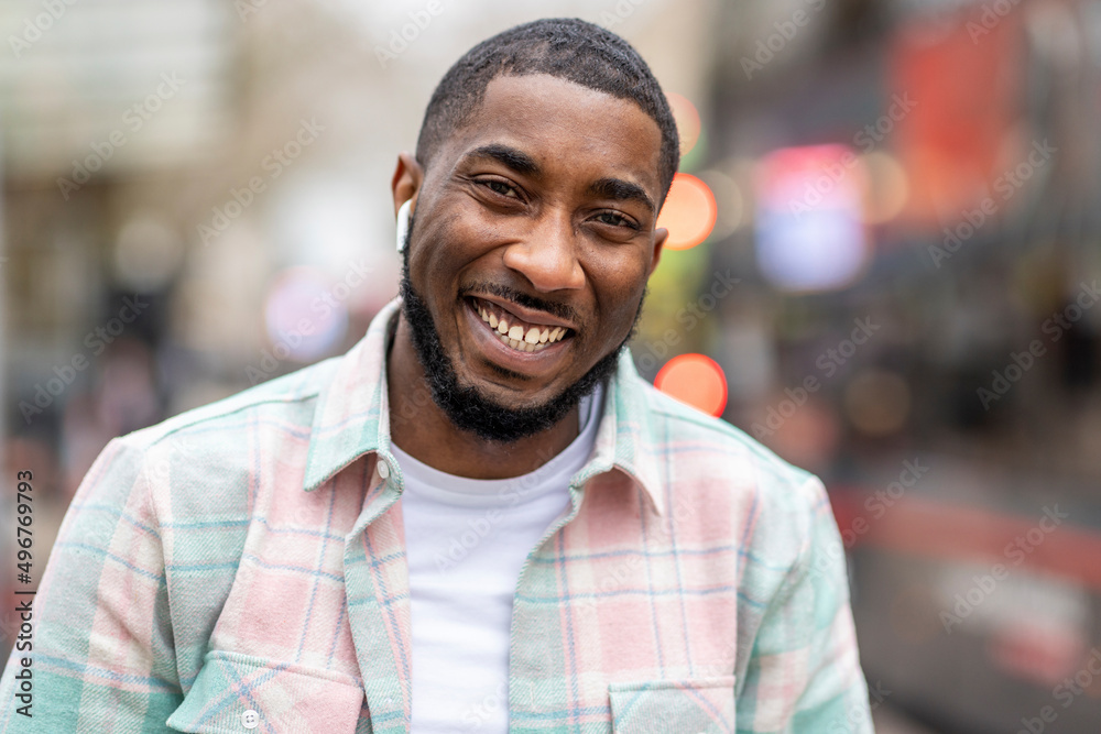 Happy man wearing wireless in-ear headphones outdoors Happy man wearing wireless in-ear headphones outdoors