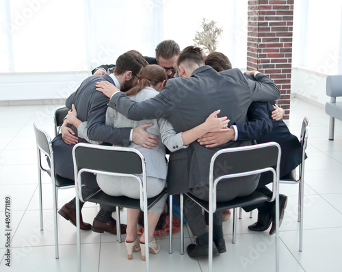 business team sits in a circle and hugs each other