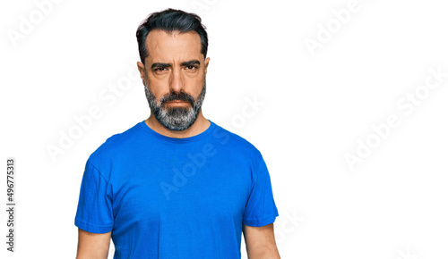Middle aged man with beard wearing casual blue t shirt skeptic and nervous, frowning upset because of problem. negative person.