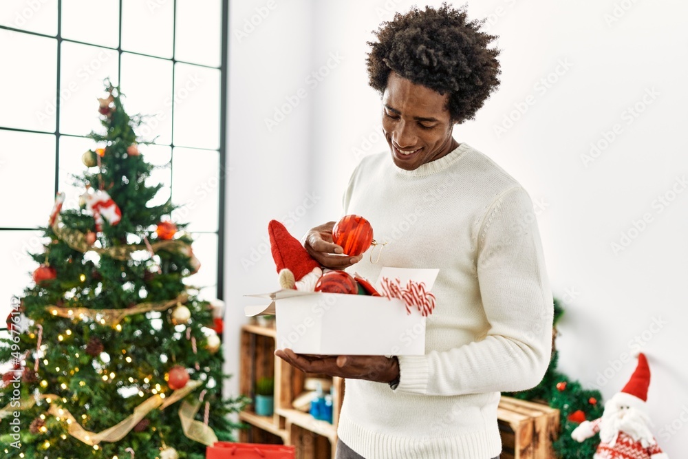 Young african american man smiling happy decorating christmas tree at home. Young african american man smiling happy decorating christmas tree at home.