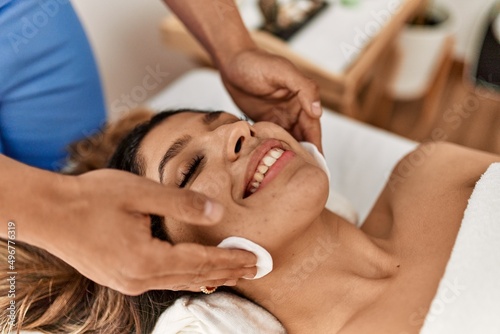 Woman smiling happy reciving skin massage with cotton pads at beauty center.
