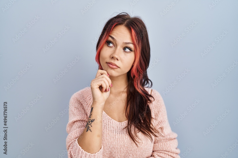 Young caucasian woman wearing pink sweater over isolated background with hand on chin thinking about question, pensive expression. smiling with thoughtful face. doubt concept. Young caucasian woman wearing pink sweater over isolated background with hand on chin thinking about question, pensive expression. smiling with thoughtful face. doubt concept.