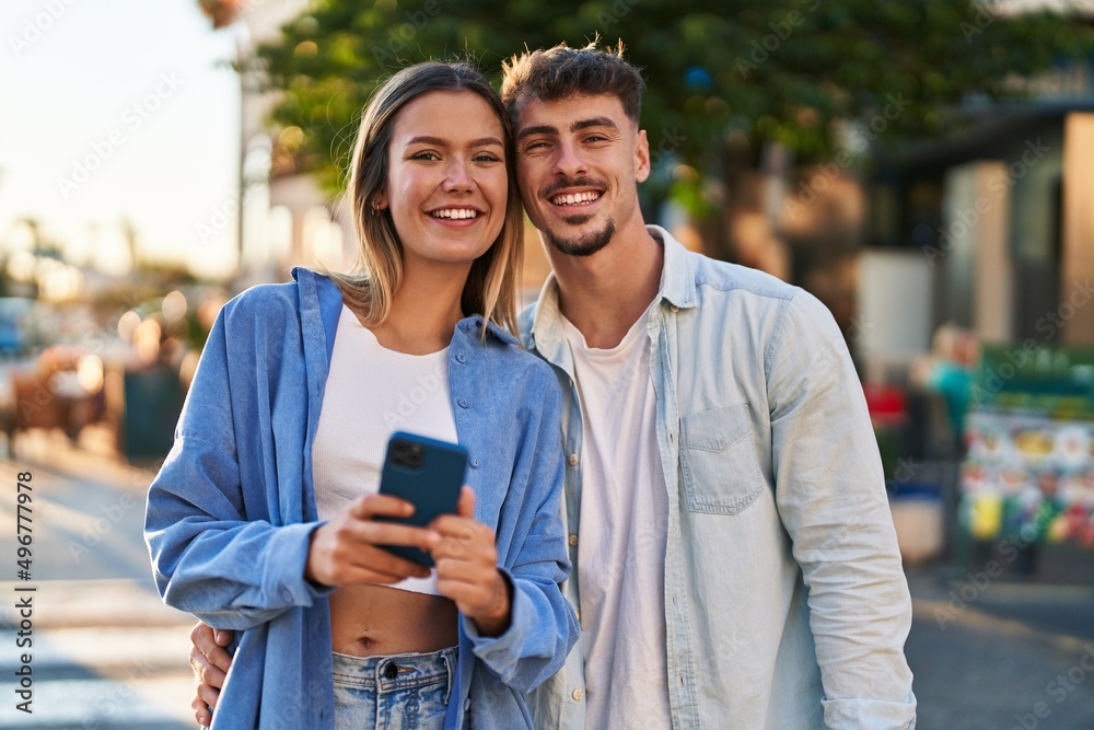 Young man and woman couple smiling confident using smartphone at street