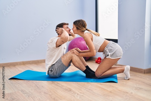 Young man and woman couple doing abs exercise kissing at sport center