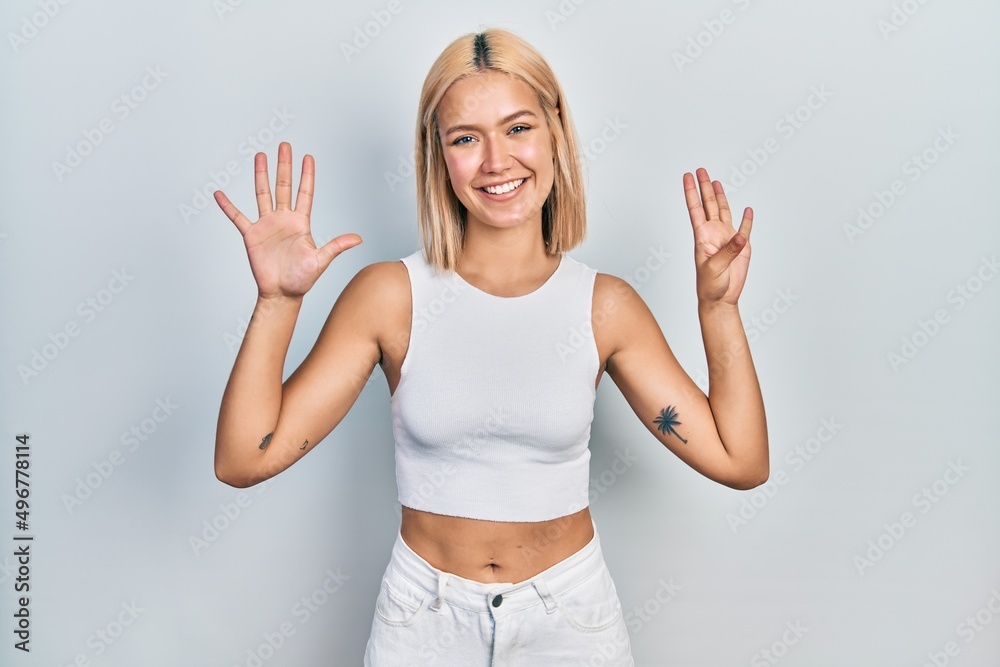 Beautiful blonde woman wearing casual style with sleeveless shirt showing and pointing up with fingers number nine while smiling confident and happy. Beautiful blonde woman wearing casual style with sleeveless shirt showing and pointing up with fingers number nine while smiling confident and happy.