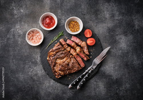 Obraz na płótnie Medium rare Ribeye steak or beef steak on the black tray with tomatoes