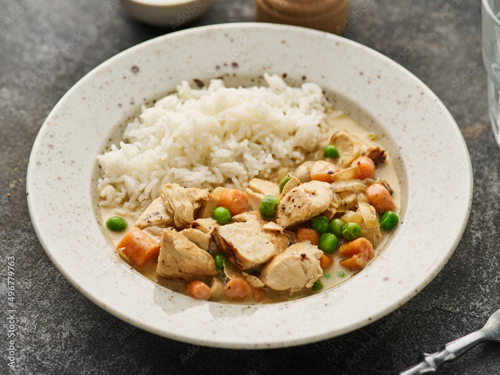 Tender chicken fillet in a creamy mushroom sauce with rice and green peas. Chicken stew with vegetables and mushroom cream sauce.