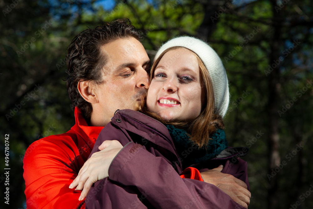 Fototapeta premium Hombre vestido con ropa invernal besando y abrazando a su pareja. Sol y frío. 