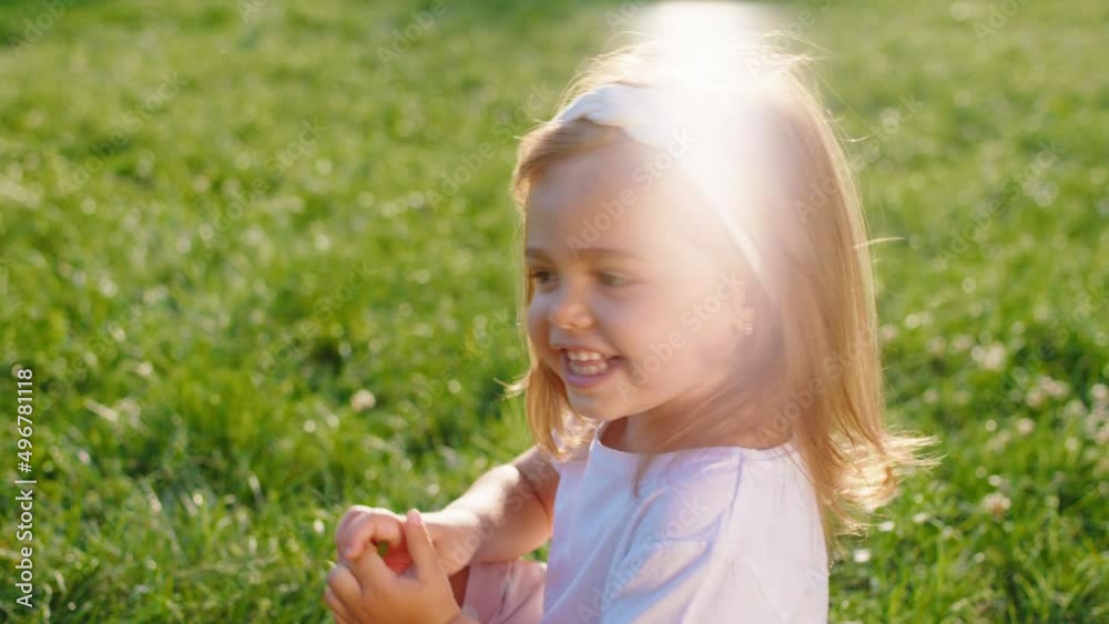 In a perfect summer day beautiful little girl closeup to the camera posing while sitting down on the grass then stand up and start to run. 4k In a perfect summer day beautiful little girl closeup to the camera posing while sitting down on the grass then stand up and start to run. 4k