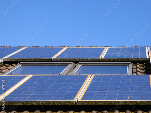Altanlage. Über 10 Jahre alte Solarpanele. Photovoltaikanlage auf dem Dach eines Einfamilienhauses neben schrägen Dachfenstern. Die Solarmodule wurden um das Fenster herum montiert. Old solar modules. photo
