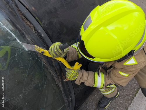 The rescue team of firefighters at the scene of the traffic accident of the car accident. Firefighters grab their tools, gear, and equipment and rush to help injured and trapped people. cutting glass