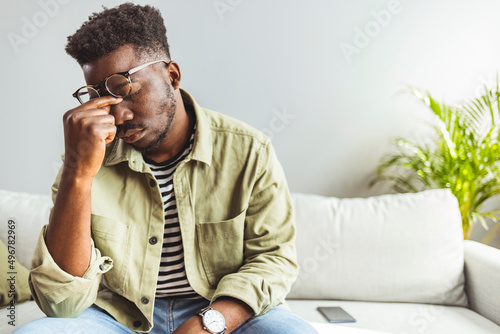 Upset stressed young african american man coping with strong headache concept, upset exhausted black guy feeling frustrated depressed tired touching forehead suffer from migraine, close up side view