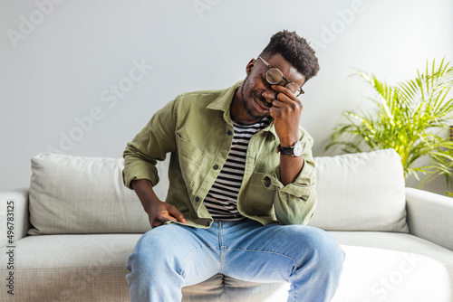 Upset african-american man squeezing head with hands, writhing in pain, suffering from headache at home, copy space. Black guy stressting and headache..