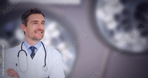 Caucasian male doctor with arms crossed smiling against hospital in background