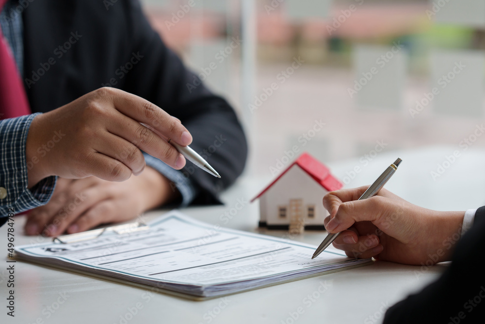 Close up of Business man pointing and signing agreement for buying house. Bank manager concept.