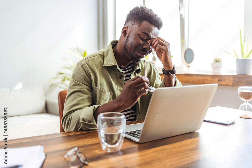 Frustrated and stressed businessman sitting at the office front a computer and holding head. Cropped shot of a handsome young businessman sitting alone in his office and suffering from a headache Frustrated and stressed businessman sitting at the office front a computer and holding head. Cropped shot of a handsome young businessman sitting alone in his office and suffering from a headache