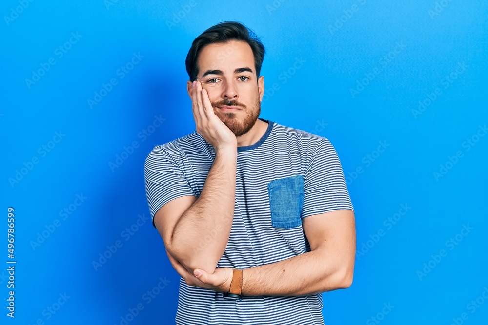 Handsome caucasian man with beard wearing casual striped t shirt thinking looking tired and bored with depression problems with crossed arms. Handsome caucasian man with beard wearing casual striped t shirt thinking looking tired and bored with depression problems with crossed arms.