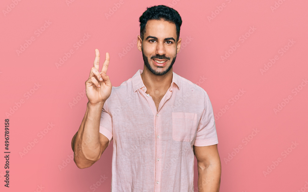 Hispanic man with beard wearing casual shirt showing and pointing up with fingers number two while smiling confident and happy. Hispanic man with beard wearing casual shirt showing and pointing up with fingers number two while smiling confident and happy.