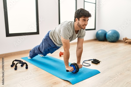 Young hispanic sporty man smiling happy training at sport center.